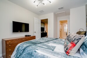 A bedroom with a bed, a dresser, a television, and a door leading to another room. - Orlando Newest Resort Community Town Home (Kissimmee)