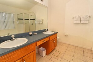 Un baño con dos lavamanos, un espejo grande y un perchero para toallas.