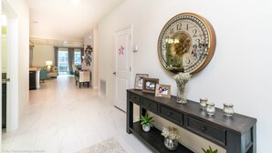 A hallway with a large wall clock, a console table with decorative items, and a door with a star decoration.