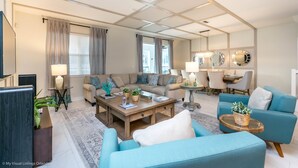 A spacious living room with a sectional sofa, a coffee table, and a dining area with a table and chairs.