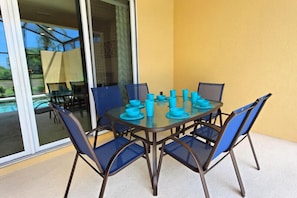 A glass-top dining table with blue chairs and matching blue tableware, set against a yellow wall.