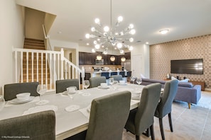 A modern kitchen with dark cabinets, a central island, and a dining area with a white table set for six.