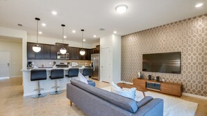 A modern kitchen with dark cabinets, a central island with bar stools, a built-in microwave, and a stainless steel refrigerator.