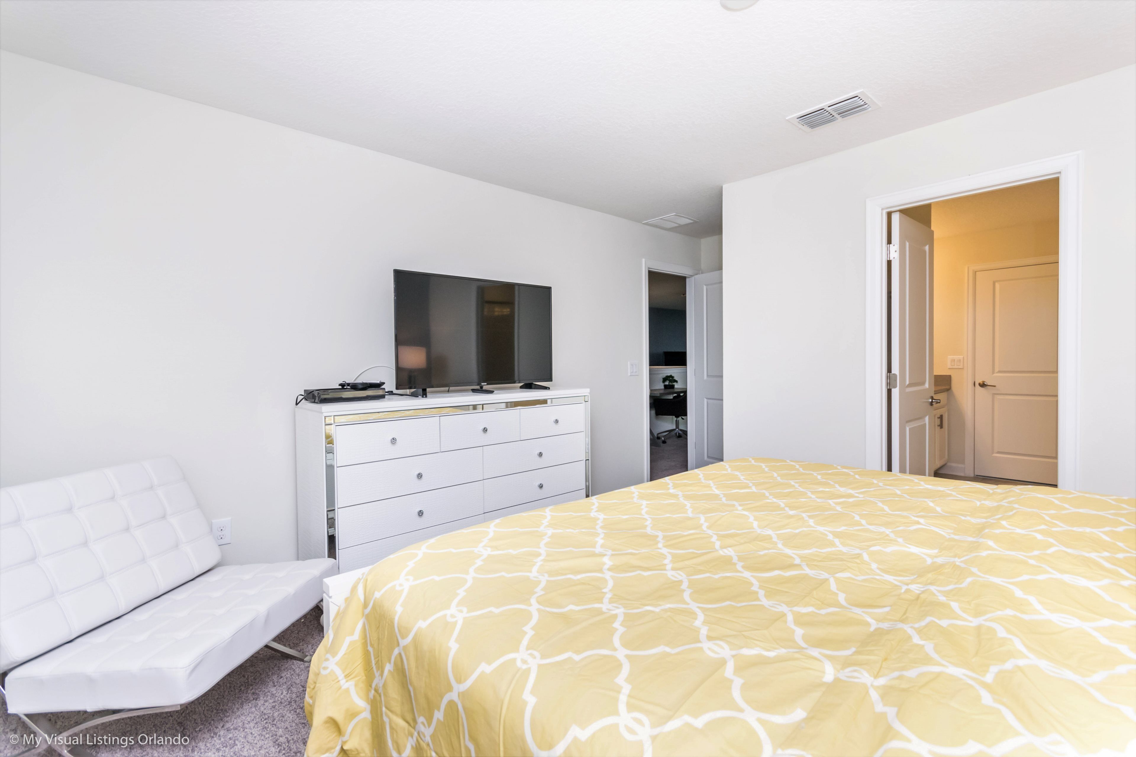 A bedroom with a bed, a white dresser, a desk, and a chair.