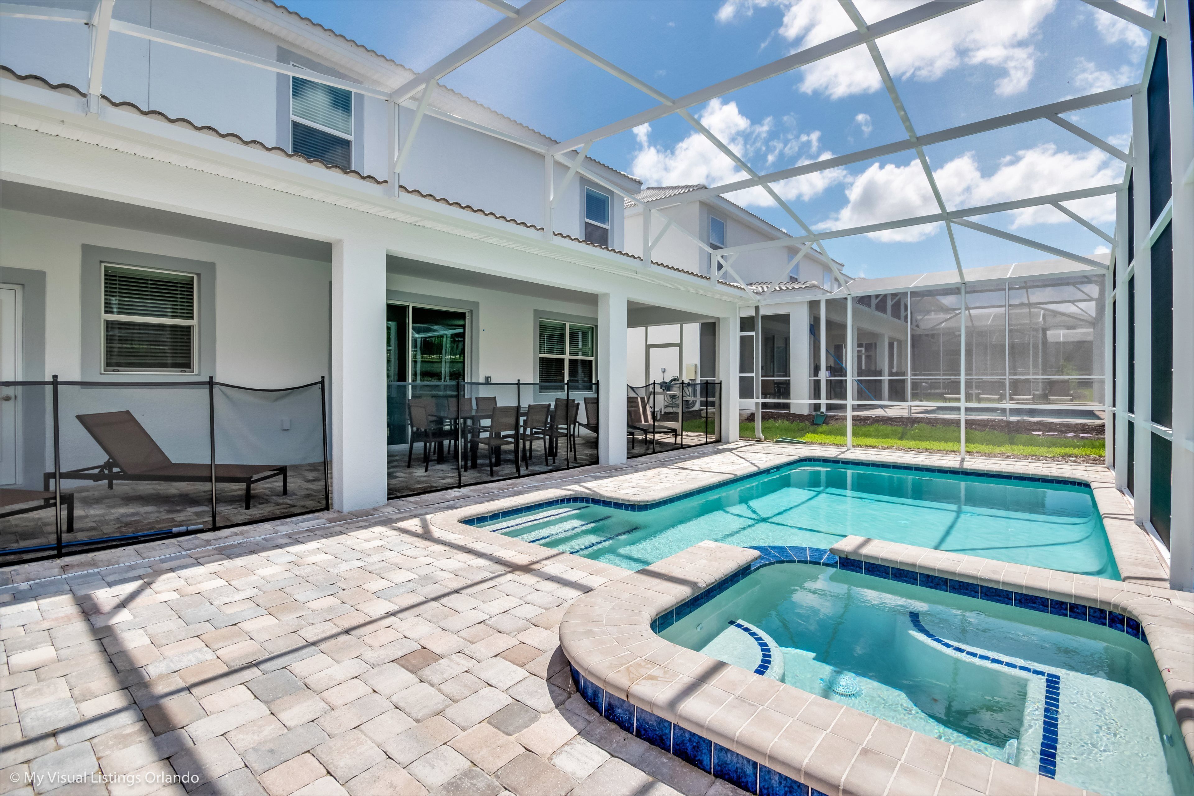 Ein Poolbereich mit Glasveranda, Liegestühlen und einer Terrasse mit Backsteinpflasterung.