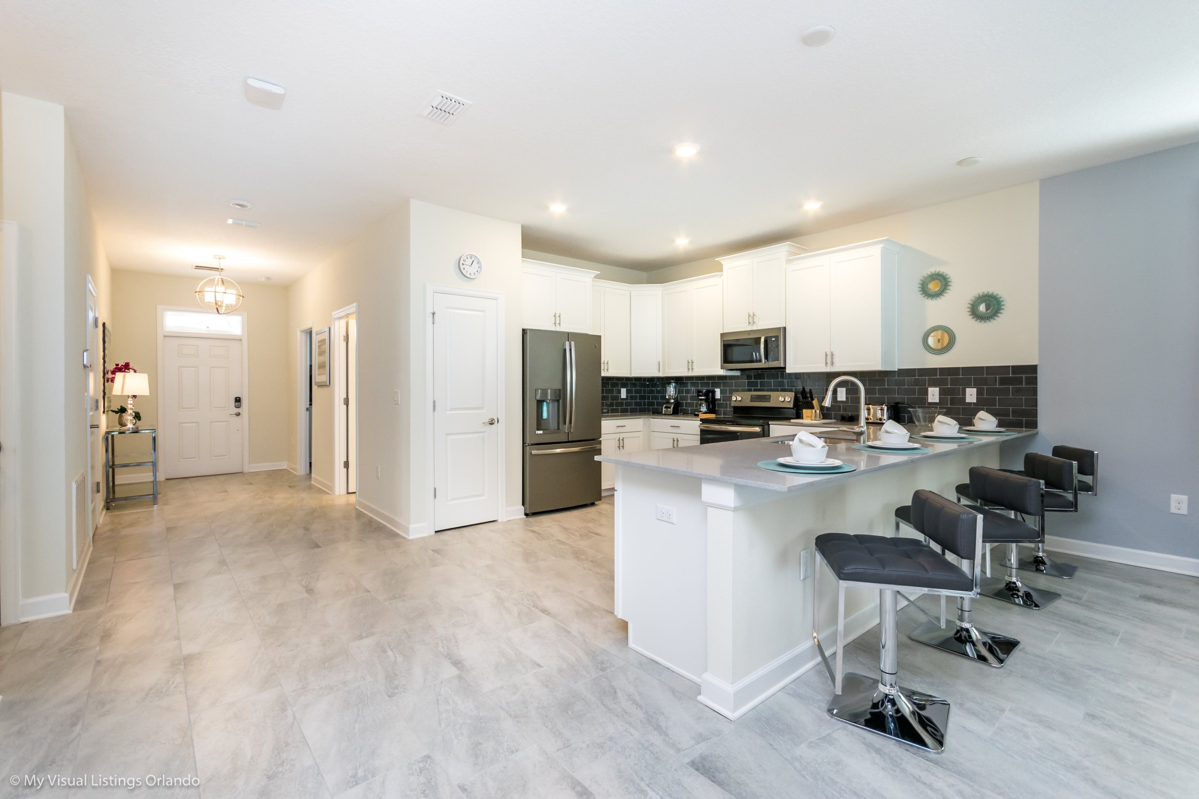 A modern kitchen with white cabinets, stainless steel appliances, and a central island with bar stools.
