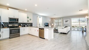 A modern kitchen with white cabinetry, stainless steel appliances, and a central island.