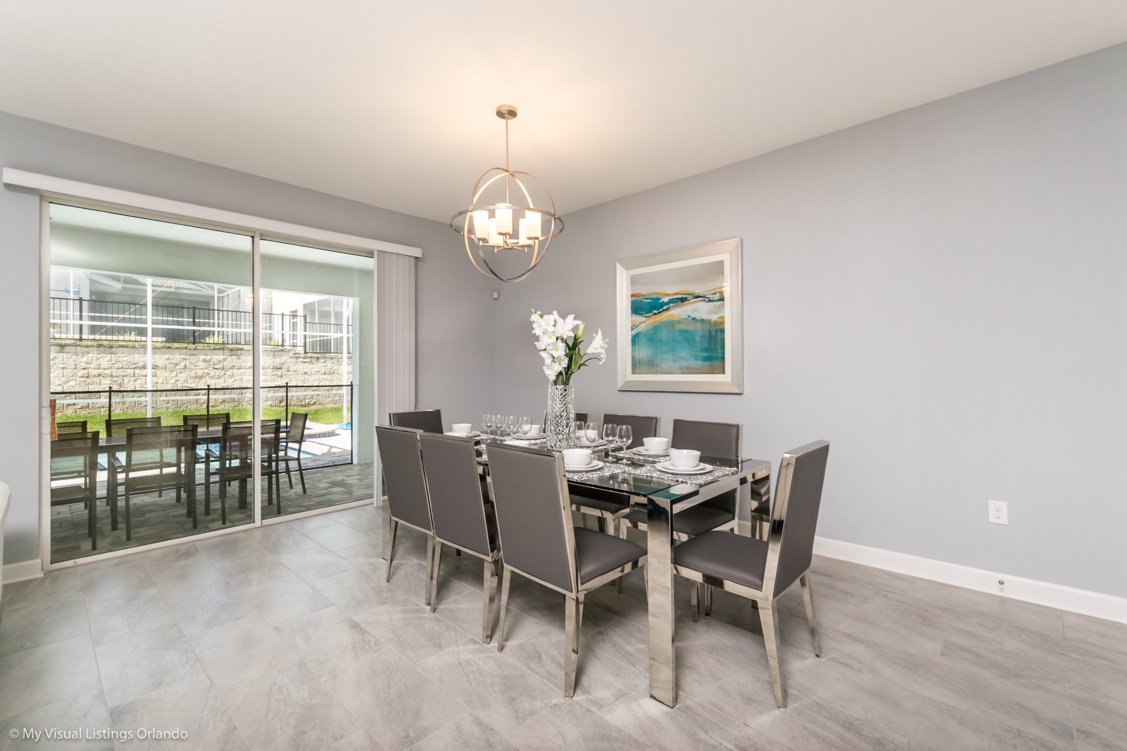 A dining area with a glass table, chairs, and a chandelier.