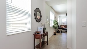 A hallway with a wooden console table, a decorative mirror, and a potted plant. - 3175tc Amazing Compass Baytown Home Sleeps 10 (Kissimmee)