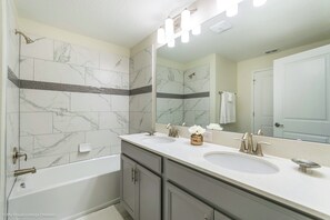 A bathroom with two sinks, a bathtub, and a large mirror with lights. - 1571sand (Davenport)