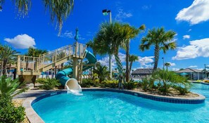 A swimming pool with a slide, palm trees, and a clear blue sky. - 1571sand (Davenport)