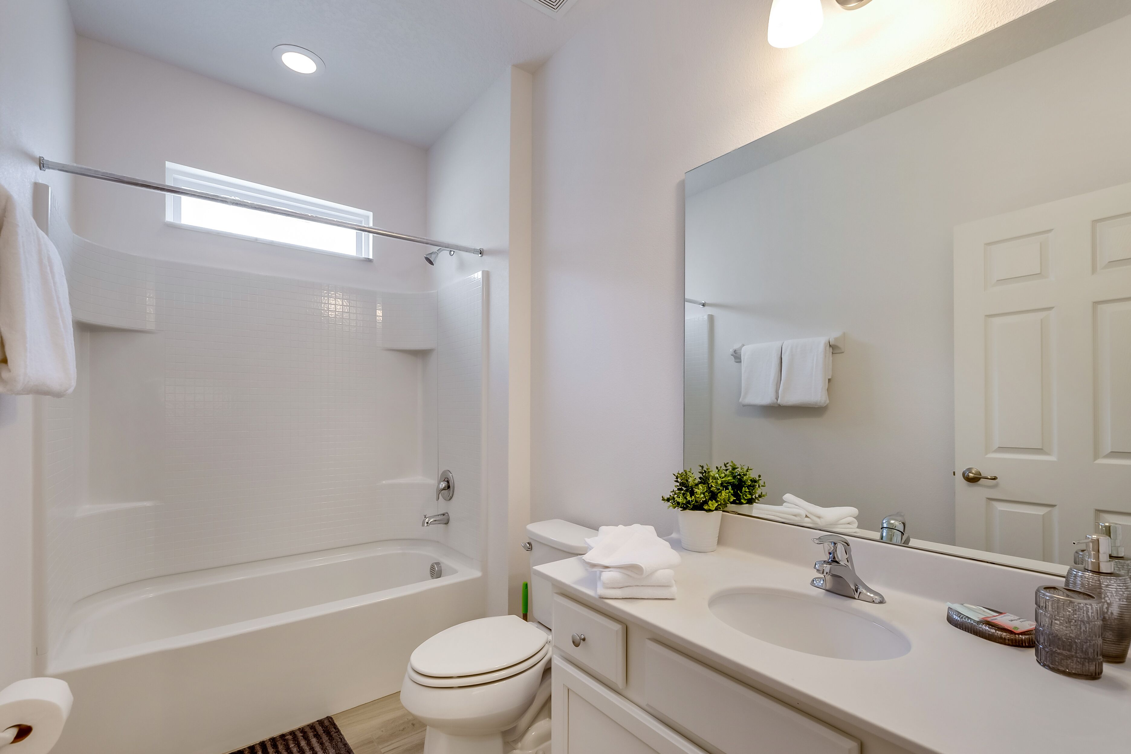 A modern bathroom with a bathtub, toilet, sink, and large mirror.