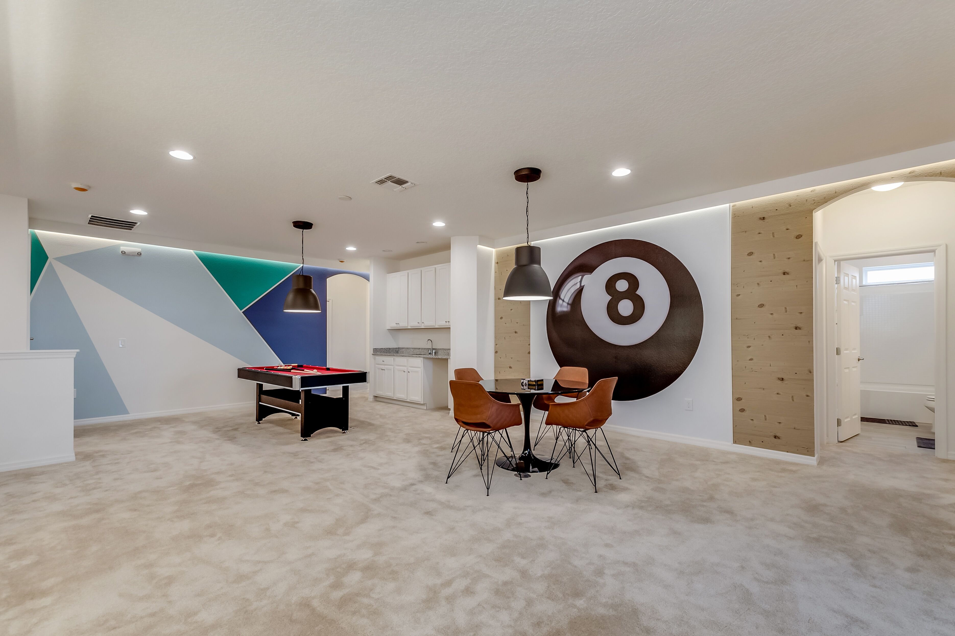 A modern living room with a pool table, a dining area, and a large wall number '8'.