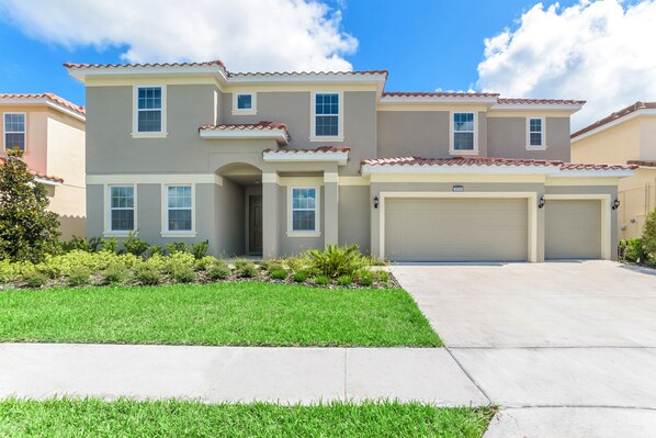 A two-story house with a garage, a well-maintained lawn, and a clear sky. - 14 Bdrm 11 Bath Villa For 30 (Davenport)