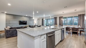 A modern kitchen with a central island, built-in appliances, and a dining area with a large window. - 14 Bdrm 11 Bath Villa For 30 (Davenport)