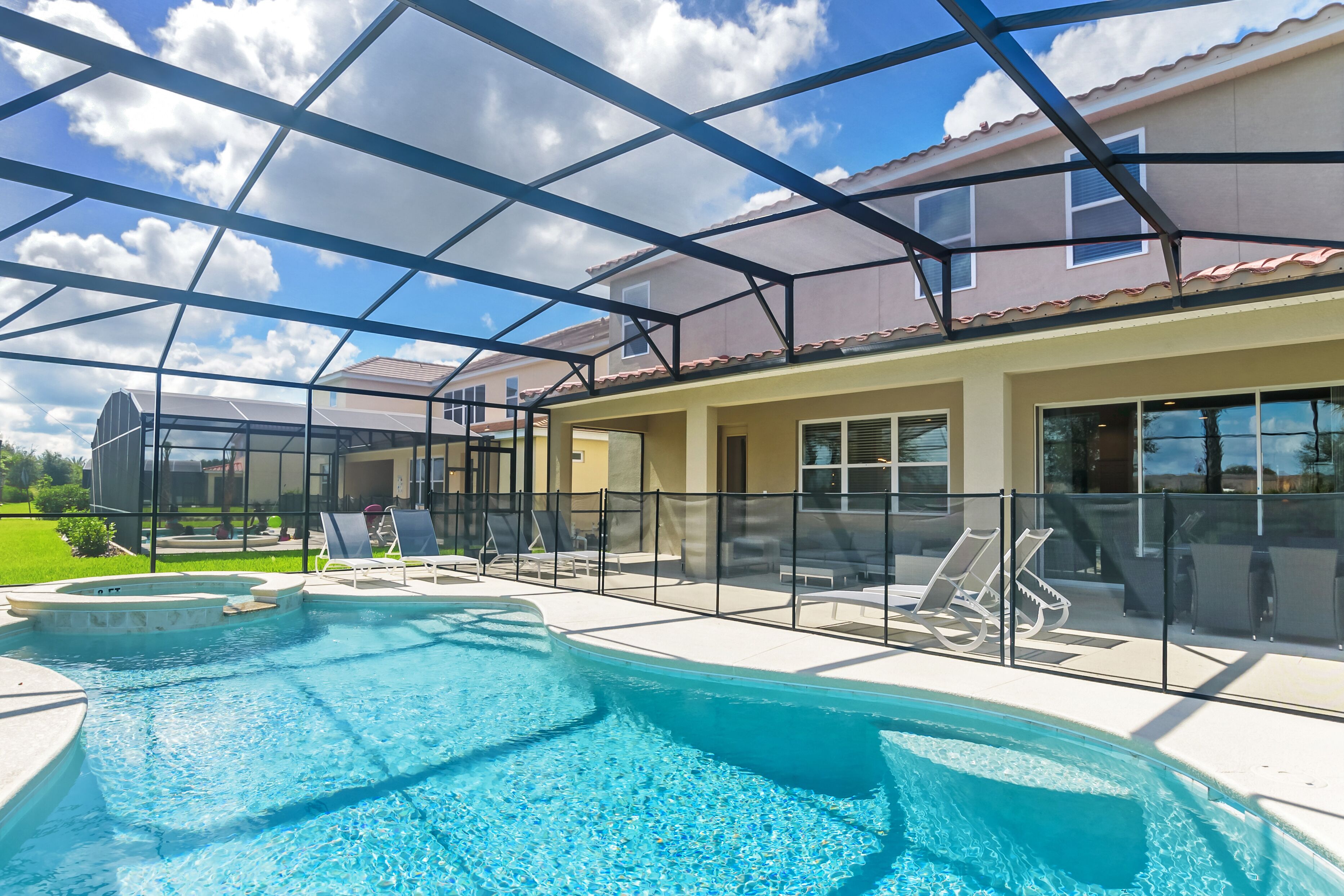 Ein Schwimmbecken mit Glasveranda, umgeben von Liegestühlen und einer überdachten Terrasse.