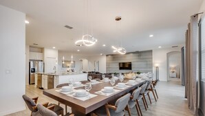 A modern kitchen with a long dining table set for six, wooden chairs, and pendant lighting. - 14 Bdrm 11 Bath Villa For 30 (Davenport)