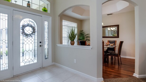 A spacious entryway with a glass door, a dining area with a table and chairs, and a large mirror on the wall. - Fantastically Decorated 4 bed 3 Bath (Davenport)