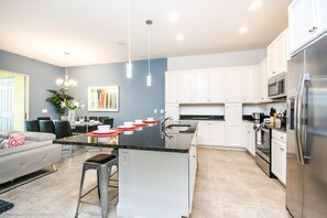 A modern kitchen with white cabinets, stainless steel appliances, and a central island with stools.