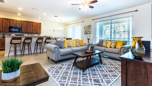 A spacious living room with a sofa, coffee table, and a dining area with bar stools. - Classic 6Bed 4Ba Villa, Games, Pool, Spa - 5244o (Davenport)