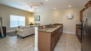 A spacious kitchen with a central island, a dining area with a sofa, and a large window. - 4 Bedroom 3 Bathroom Town Home With Pool (Kissimmee)