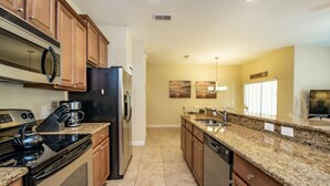 A modern kitchen with granite countertops, stainless steel appliances, and wooden cabinets. - 4 Bedroom 3 Bathroom Town Home With Pool (Kissimmee)