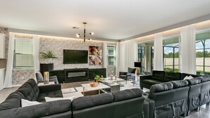 A modern living room with a sectional sofa, a flat-screen TV, and a fireplace. - 1834cvt New Solara 9 Bedroom 6 Bathroom Resort (Kissimmee)