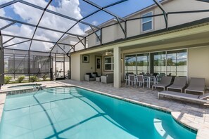 A pool area with a glass enclosure, outdoor seating, and a view of the surrounding landscape. - 1834cvt New Solara 9 Bedroom 6 Bathroom Resort (Kissimmee)