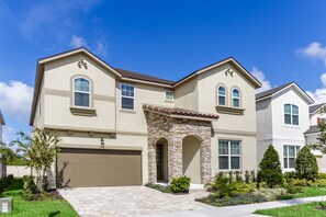 A two-story house with a beige facade, a stone entrance, and a garage. - 1834cvt New Solara 9 Bedroom 6 Bathroom Resort (Kissimmee)