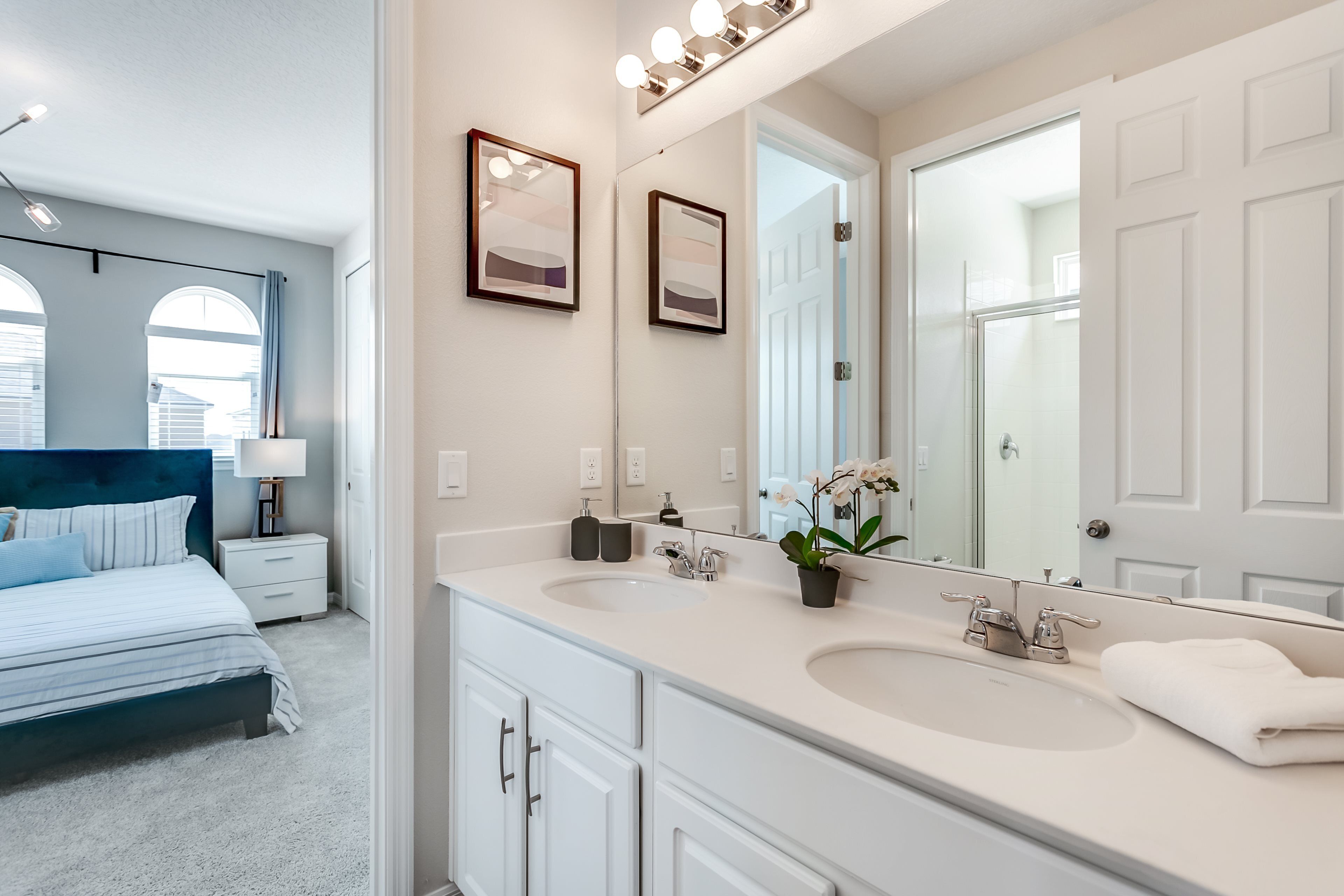 A modern bedroom with a large bed, two bedside tables, a nightstand, and a large mirror.