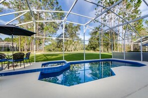 Una piscina cubierta al aire libre con vistas despejadas a un césped cuidado y árboles al fondo.