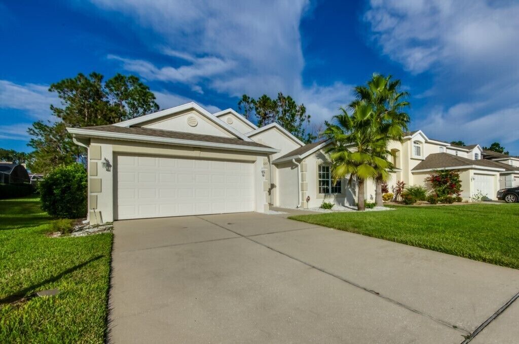 A residential house with a garage, a driveway, and a well-maintained lawn.