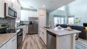 A modern kitchen with granite countertops, stainless steel appliances, and a central island.