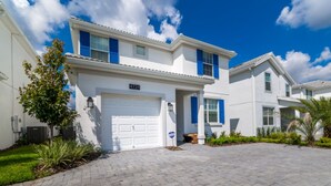 A modern two-story house with a white exterior and blue shutters, a paved driveway, and a well-maintained lawn.