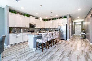 A modern kitchen with white cabinets, a granite countertop, and a central island with bar stools.