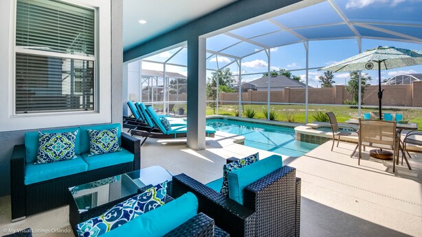 Un espacio al aire libre techado con piscina, asientos y vista al patio trasero.