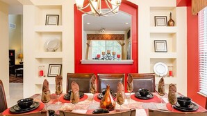 Comedor con una pared de acento roja, una araña y certificados enmarcados en las paredes.