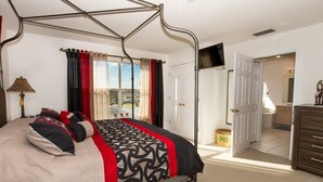 A four-poster bed with a patterned bedspread, a lamp, and a television on the wall. - 353 Glen (Davenport)