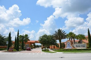 A gated entrance with a sign reading 'Bella Vida' and a red car parked in front.