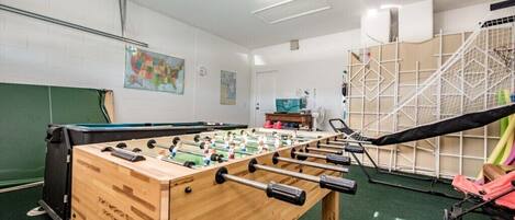 Una habitación con mesa de futbolín, mesa de billar y trampolín.