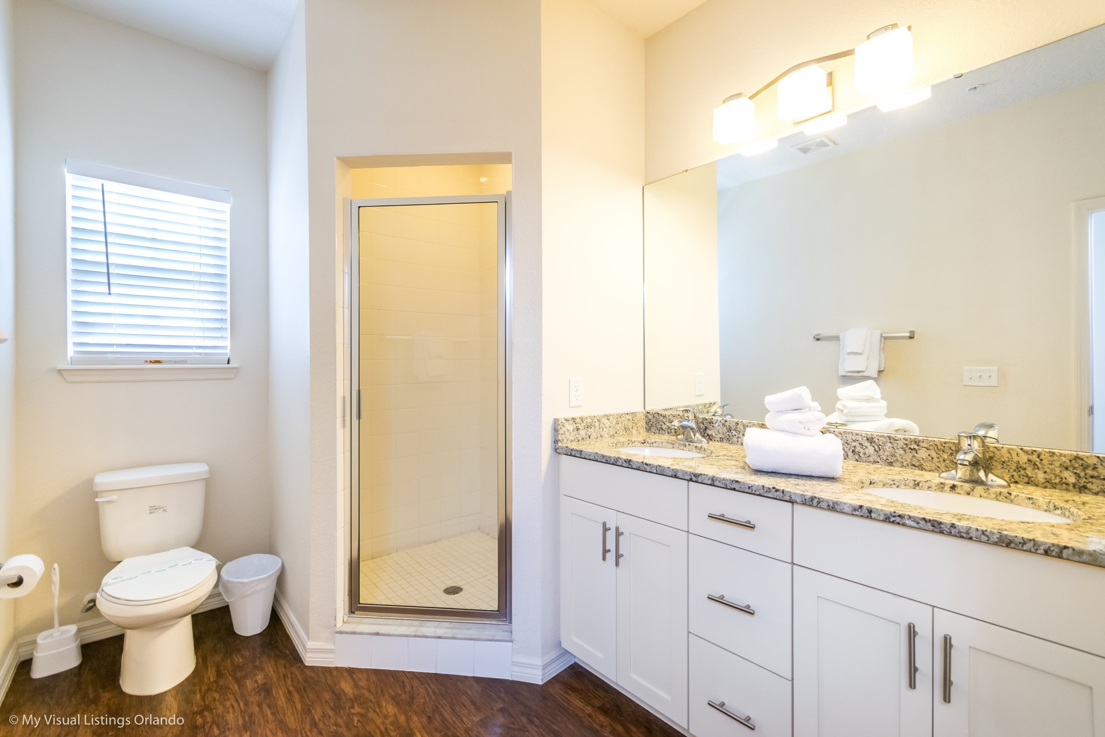 A bathroom with a shower, toilet, sink, and vanity.