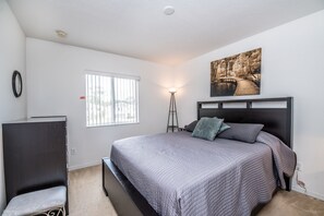 A bedroom with a bed, a window, a painting, and a lamp. - 4701rrl (Kissimmee)