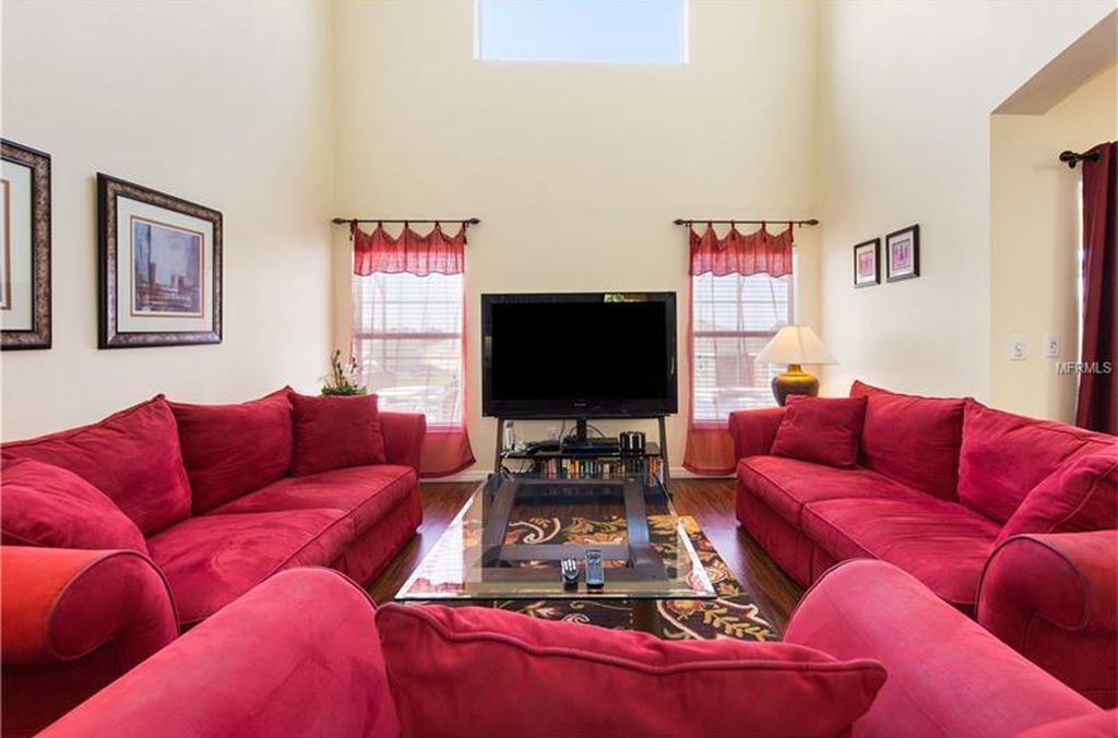 A living room with two red sofas, a flat-screen TV, and a coffee table.