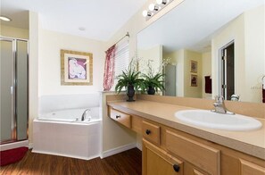 A modern bathroom with a bathtub, a sink, a large mirror, and a potted plant. - Emerald Resort 5 Bedroom 3 Bathroom Villa (Kissimmee)