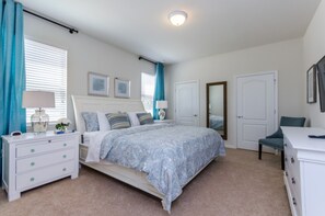 A bedroom with a bed, nightstands, a dresser, and a mirror.