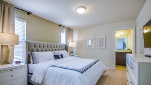 Une chambre à coucher avec un grand lit, des tables de chevet, une commode, une lampe, un miroir et une coiffeuse.