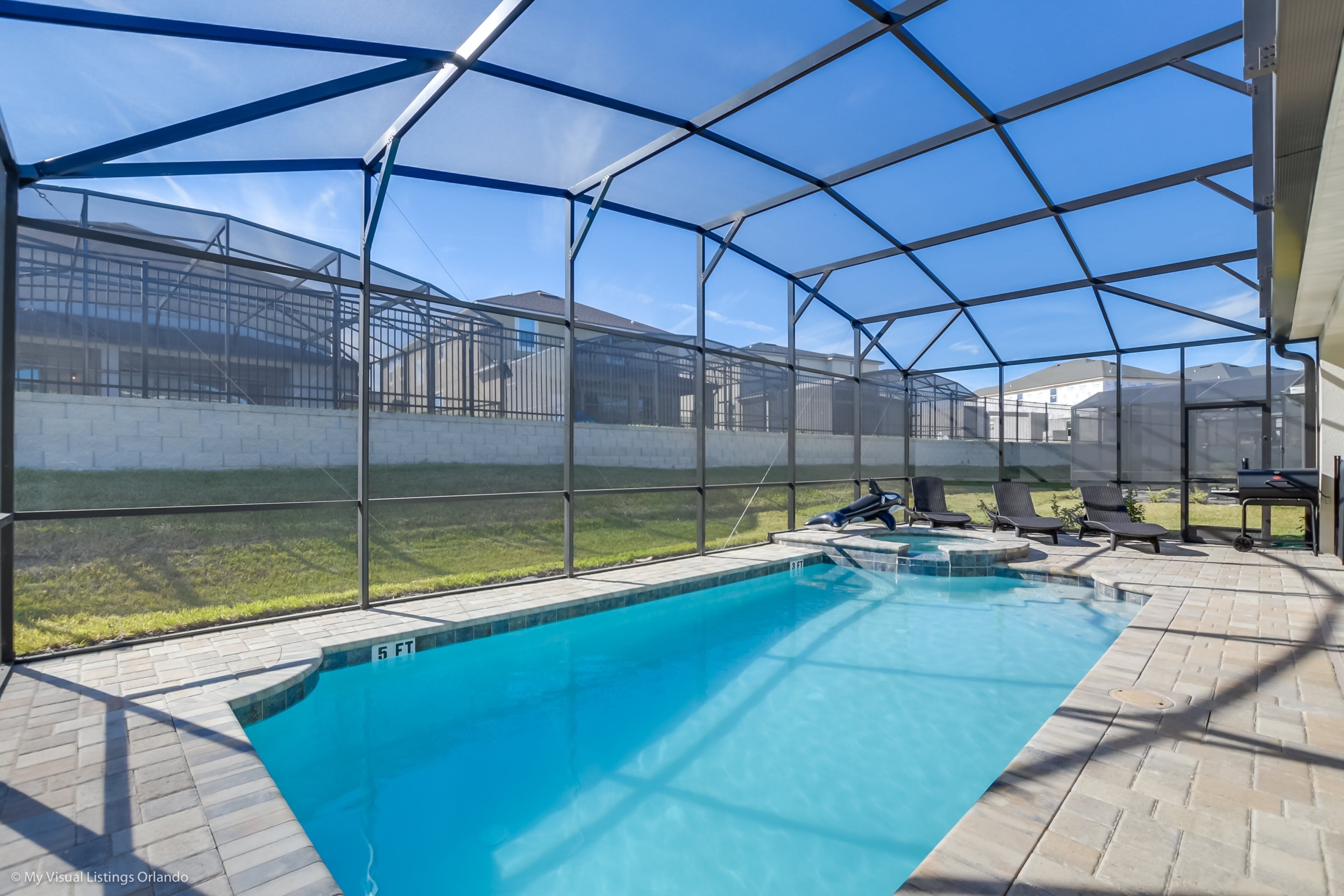 An indoor swimming pool with a clear view of the surrounding area through a glass enclosure.
