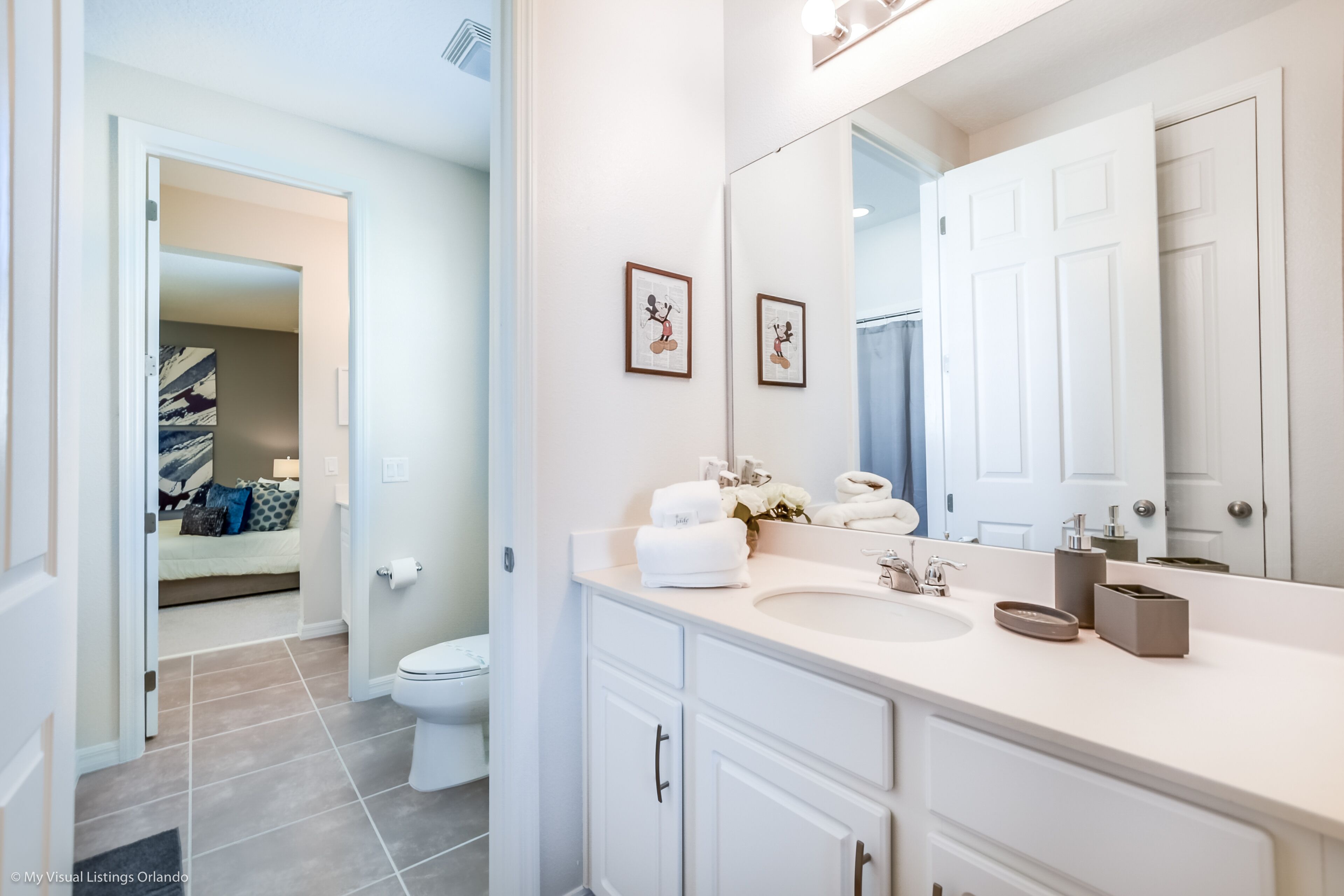 A modern bathroom with a white vanity, a large mirror, and a toilet.