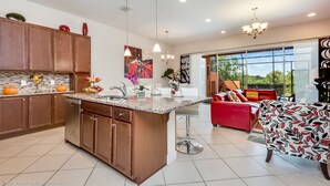 Una cocina moderna con una isla central, armarios de madera e iluminación colgante.