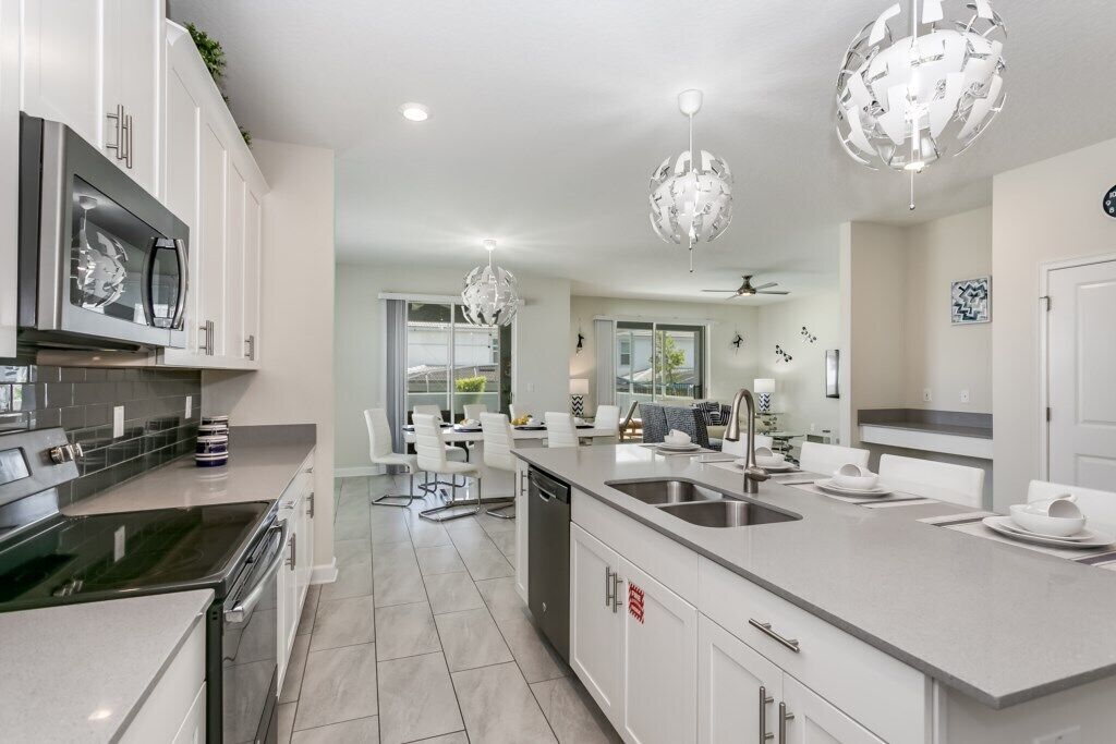 A modern kitchen with white cabinetry, stainless steel appliances, and a large island with a sink.